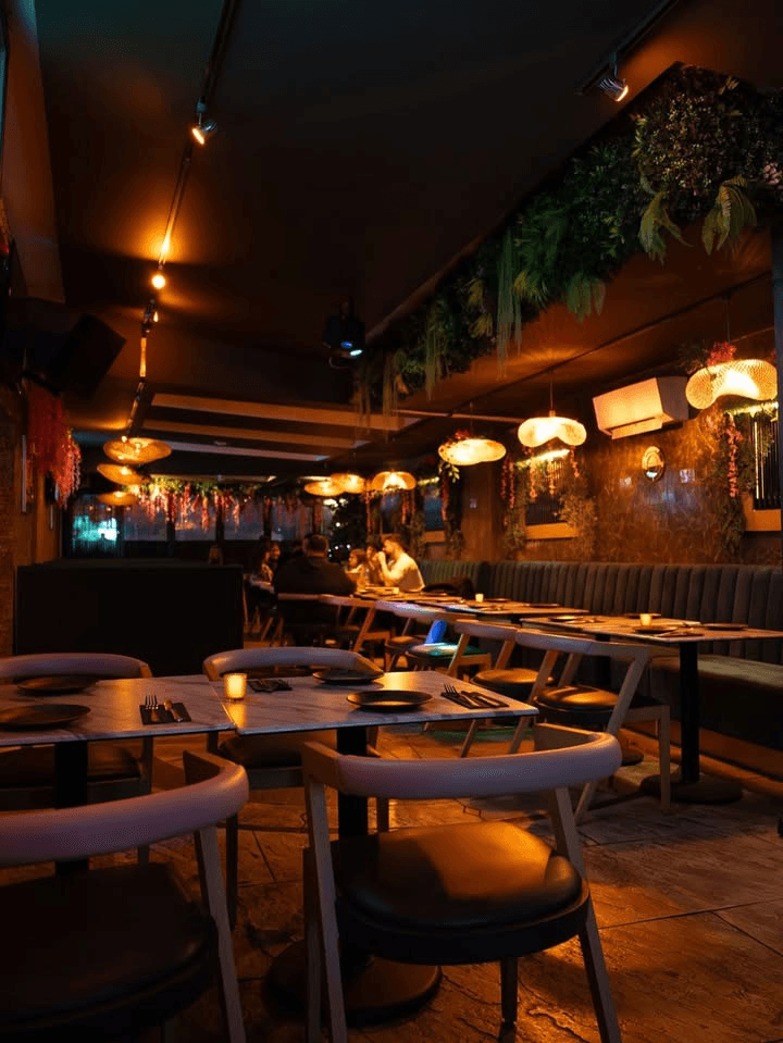 The lounge at night, with candles on marble tables and hanging lamps