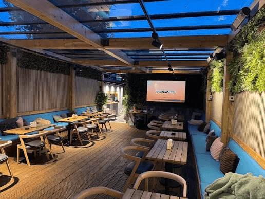 The covered terrace at Azuro with wooden tables and blue banquettes